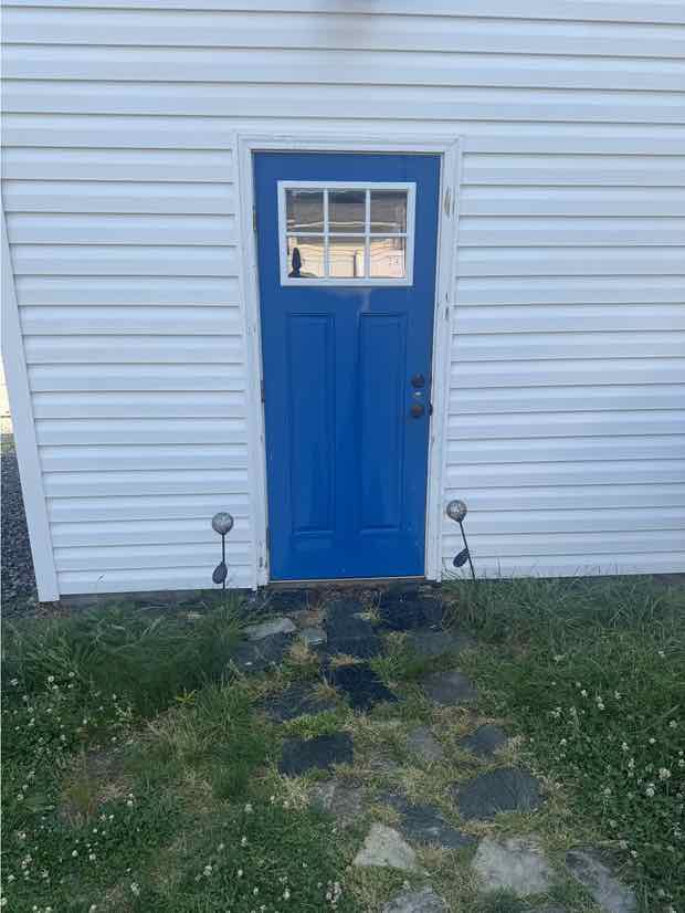 The same entry after soft washing — the siding is clean and white to the ground.
