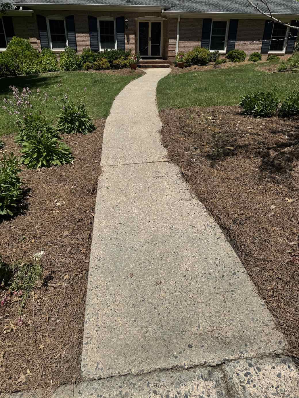 The same walkway after washing — pale, clean concrete with the aggregate visible again.